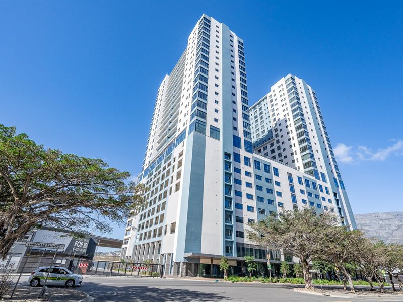 Exterior view of a modern high-rise apartment building featuring a contemporary glass and concrete facade, situated in an urban setting.