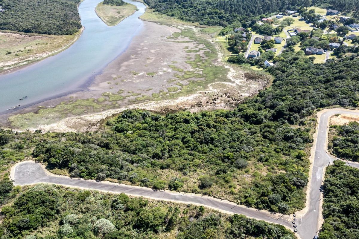 Aerial view of a vacant residential plot featuring established vegetation, adjacent to a river and local road infrastructure.