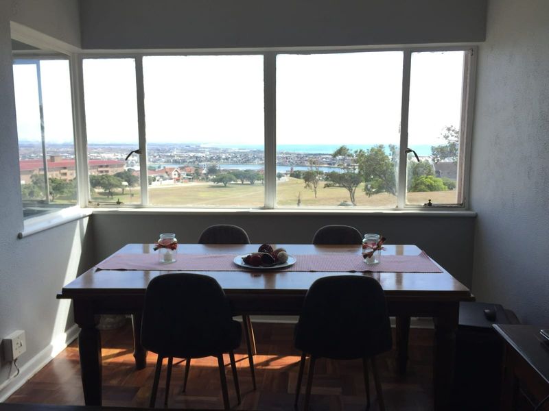 Dining area featuring large windows with expansive coastal and landscape views, complemented by classic parquet flooring.