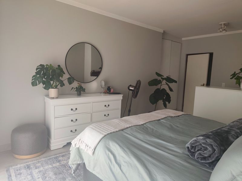 A well-maintained bedroom featuring neutral wall tones, built-in storage cupboards, and a functional layout with ample space.