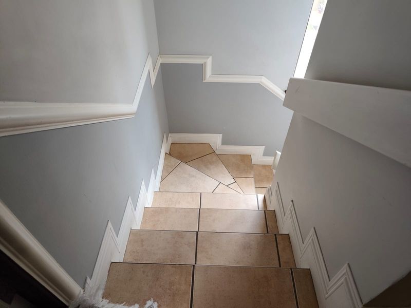 A staircase featuring tiled steps and decorative wall molding, providing a clean and functional transition between levels.