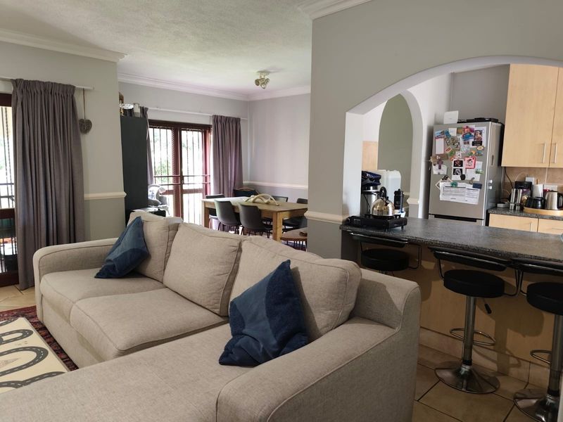 Open-plan living and dining area featuring a breakfast bar, tiled flooring, and an arched transition into the kitchen space.