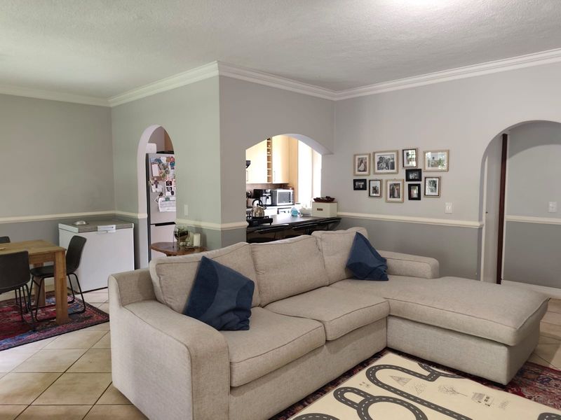 Open plan living area featuring arched doorways, crown molding, and chair rail detailing, with a view into the adjacent kitchen space.