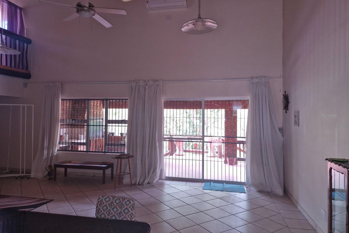 Spacious living area with high ceilings, tiled flooring, ceiling fans, and large sliding glass doors providing access to an outdoor patio.