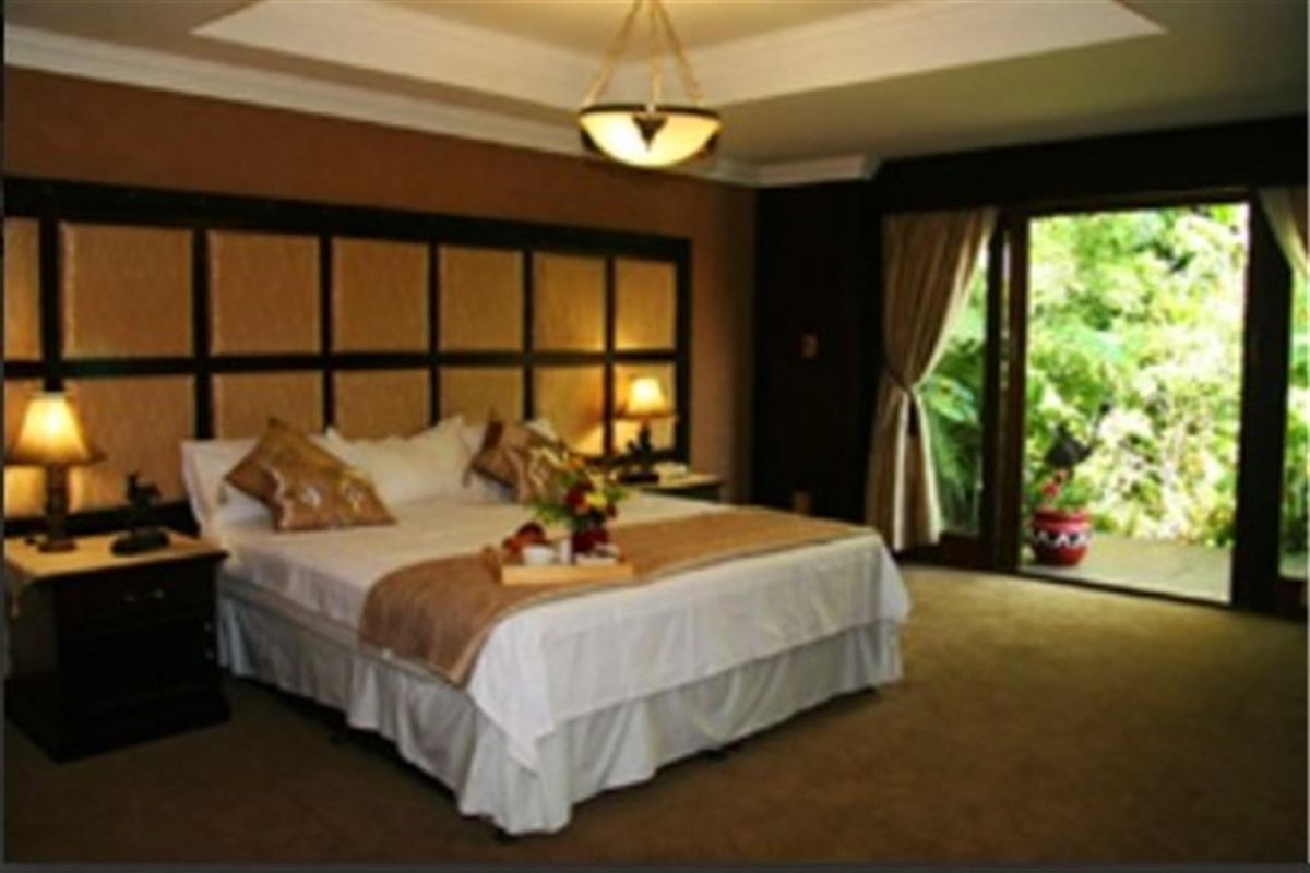 Spacious bedroom featuring a large built-in headboard, recessed ceiling detail, and sliding glass doors opening to a private outdoor area.