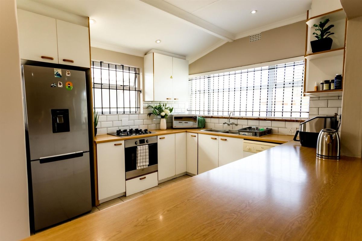 A well-maintained kitchen featuring white cabinetry, wooden countertops, subway tile backsplash, built-in oven, gas hob, and stainless steel sink.