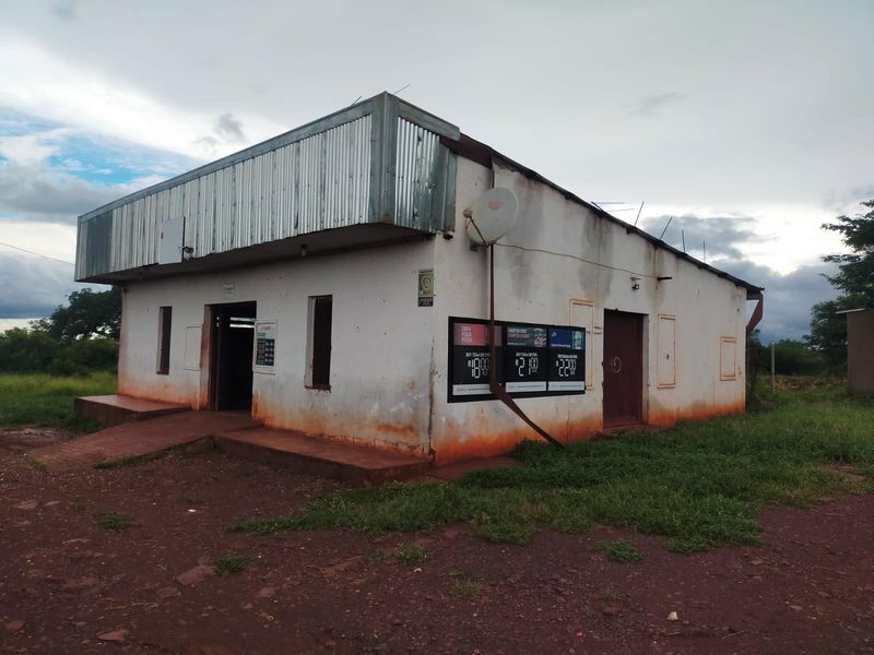 Exterior view of a commercial building featuring a corrugated metal fascia, concrete ramp access, and visible exterior wall weathering.