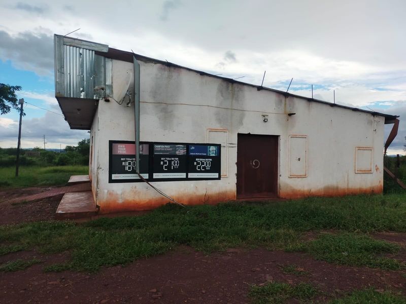 Exterior view of a commercial building featuring a metal roof, concrete ramp, and weathered wall finishes with prominent signage.