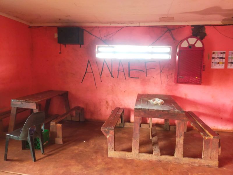 Interior space featuring red painted walls with graffiti, exposed wiring, and a horizontal window. The area requires significant maintenance and cosmetic renovation.