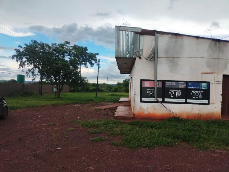 Exterior view of a commercial building featuring masonry walls, corrugated metal roof detailing, and prominent external advertising signage on the side facade.