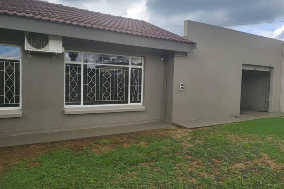 Rear view of the property featuring a tiled roof, security-barred windows, an external air conditioning unit, and a grass lawn area.