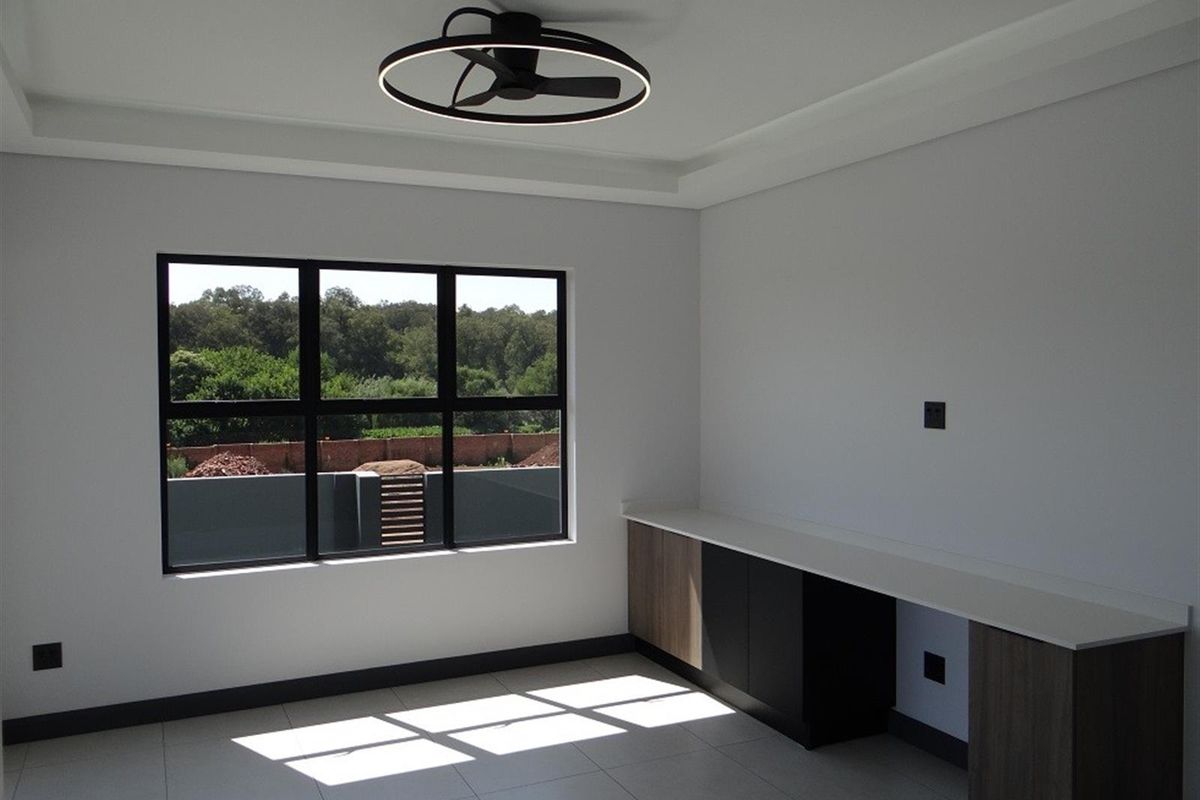 A modern, bright bedroom featuring tiled flooring, built-in cabinetry with a stone countertop, and a contemporary ceiling fan with integrated lighting.