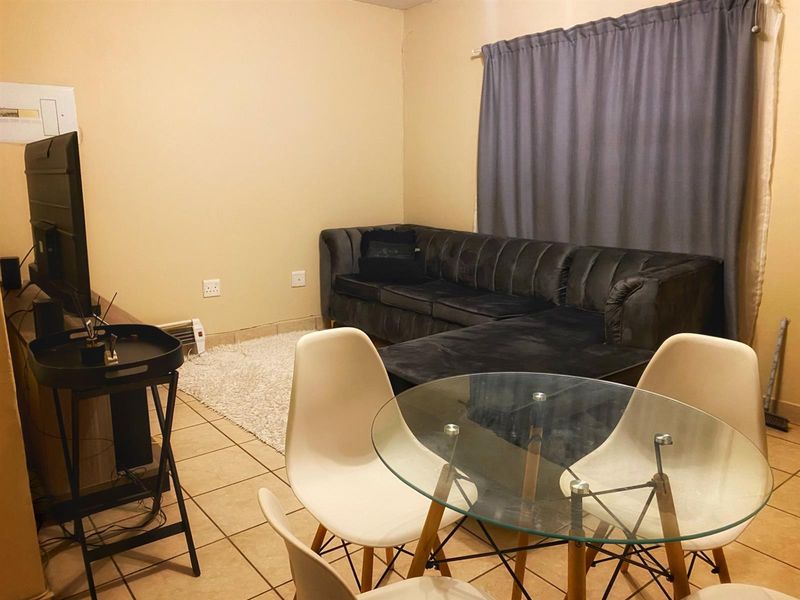 An open-plan living and dining area featuring tiled flooring and neutral wall finishes, providing a functional space for relaxation and meals.