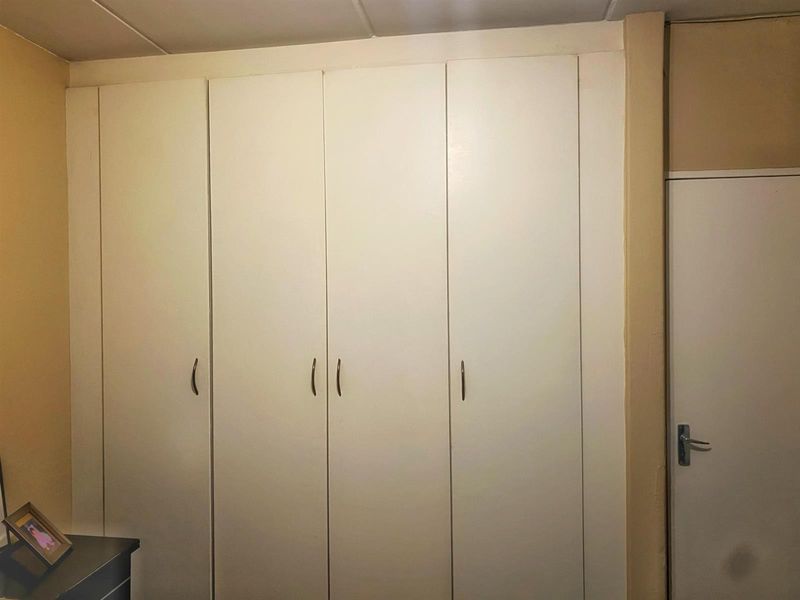 A bedroom featuring floor-to-ceiling built-in cupboards with white doors and modern handles.