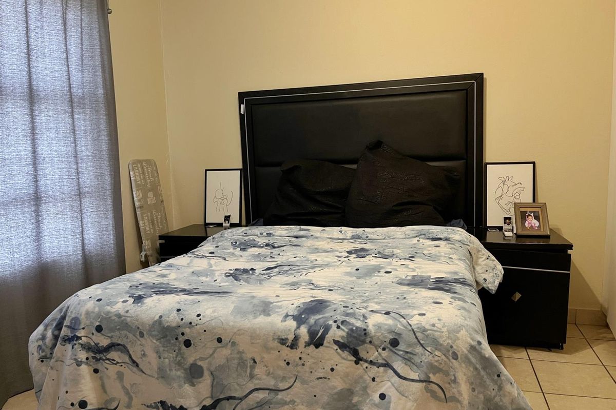 A bedroom featuring tiled flooring and neutral wall finishes, providing a functional space for rest.