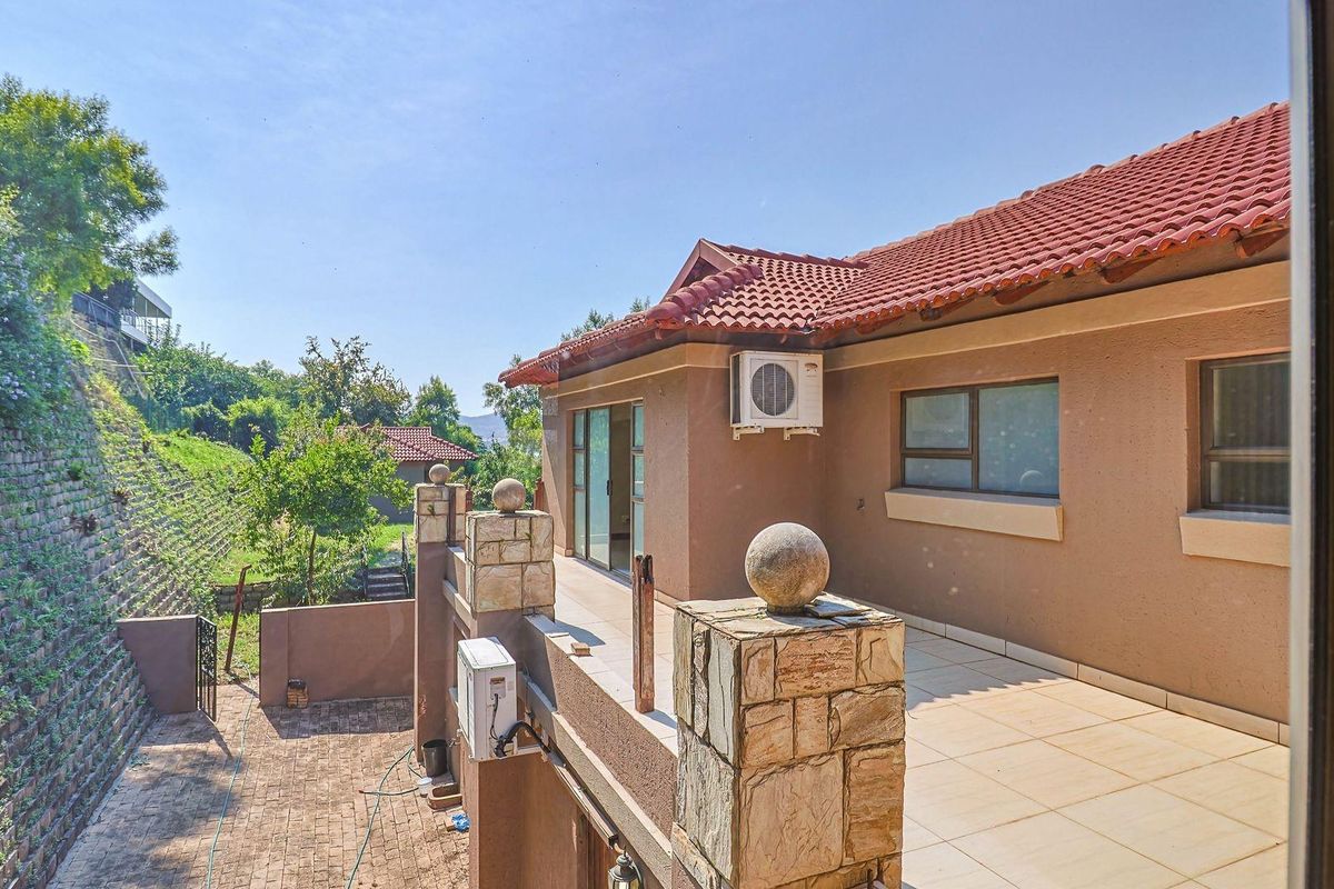 A view of the rear exterior patio featuring tiled flooring, stone-clad pillars, and wall-mounted air conditioning units.