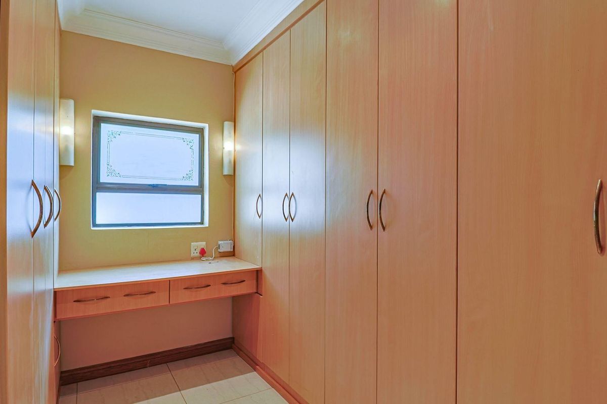 A bedroom featuring extensive built-in wooden cabinetry and a dedicated integrated desk area with a window.
