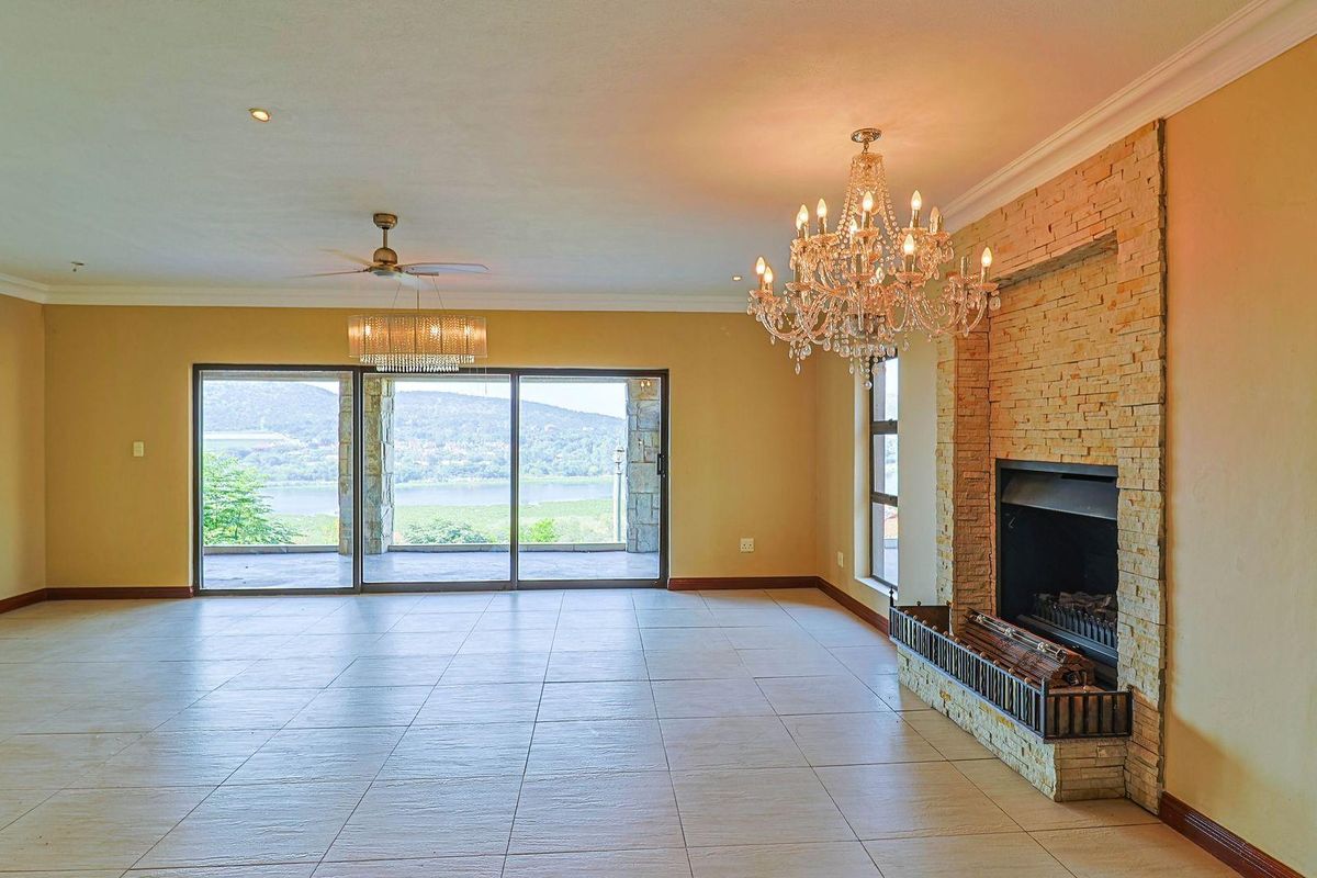 Spacious living area featuring large sliding glass doors, a stone-clad fireplace, and tiled flooring, offering scenic views and access to an outdoor patio.