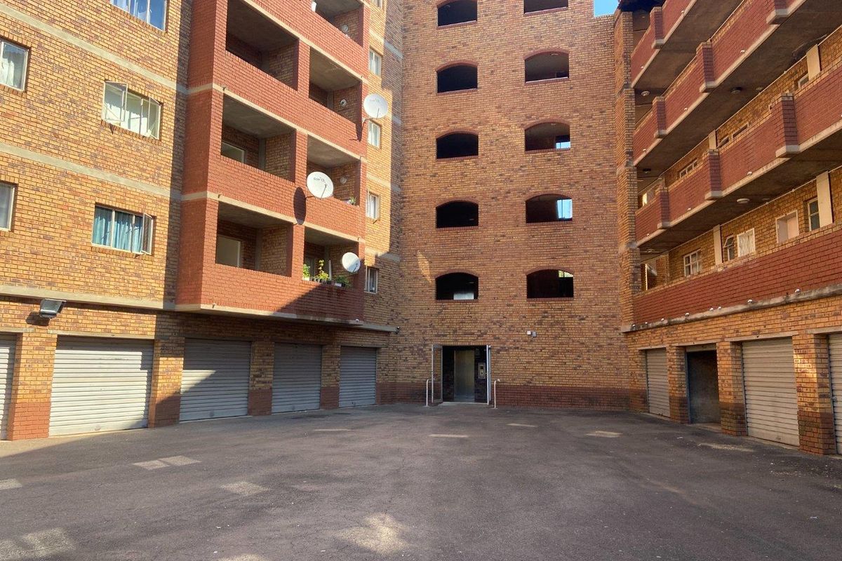 Exterior view of an apartment complex featuring face-brick facade, multiple balconies, and ground-level garage access.
