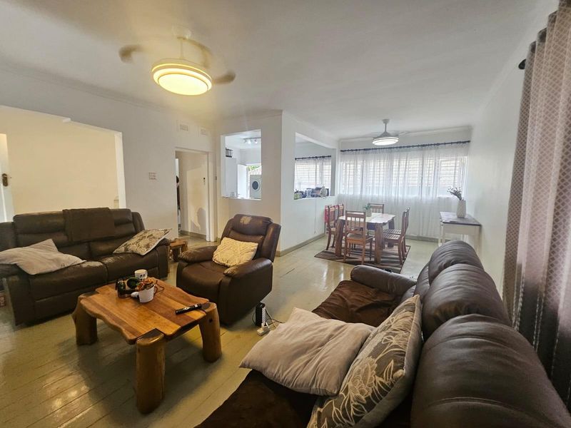 Spacious open-plan living and dining area featuring hardwood flooring, ceiling fans, and a connected layout leading to the kitchen area.