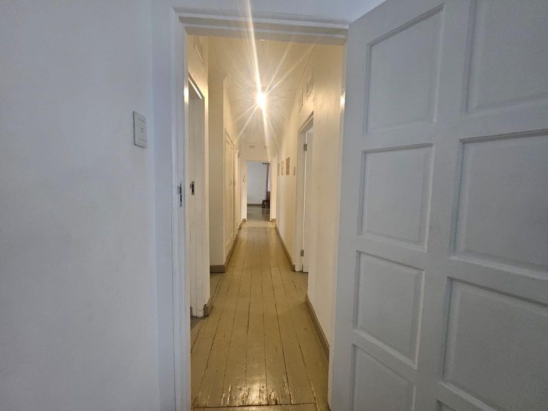 A long interior hallway featuring timber flooring and multiple built-in storage cupboards, providing access to various rooms within the home.