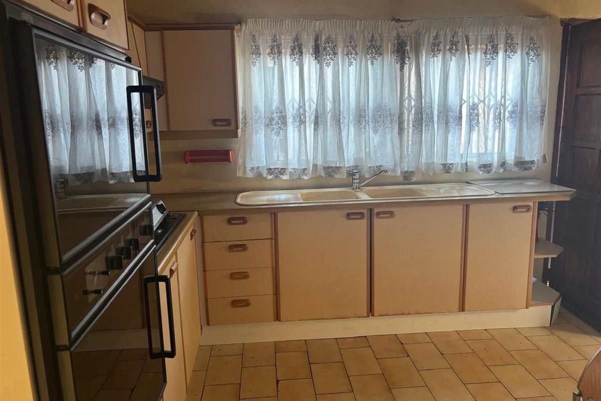 A dated kitchen featuring original cabinetry, a built-in oven, and a double sink, offering significant potential for a modern renovation.