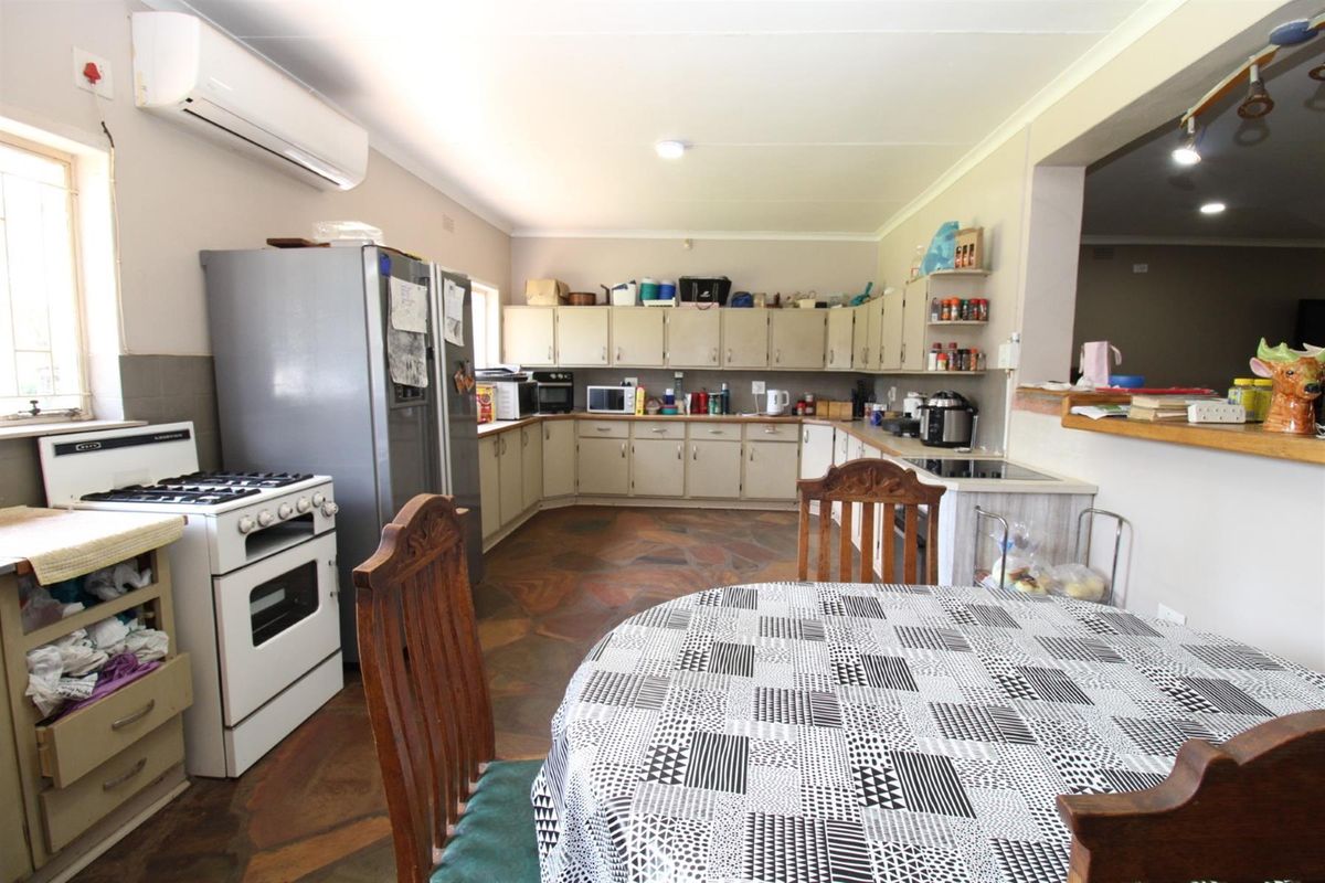A spacious kitchen featuring extensive built-in cabinetry, a gas stove, and a wall-mounted air conditioning unit, with a breakfast nook area.