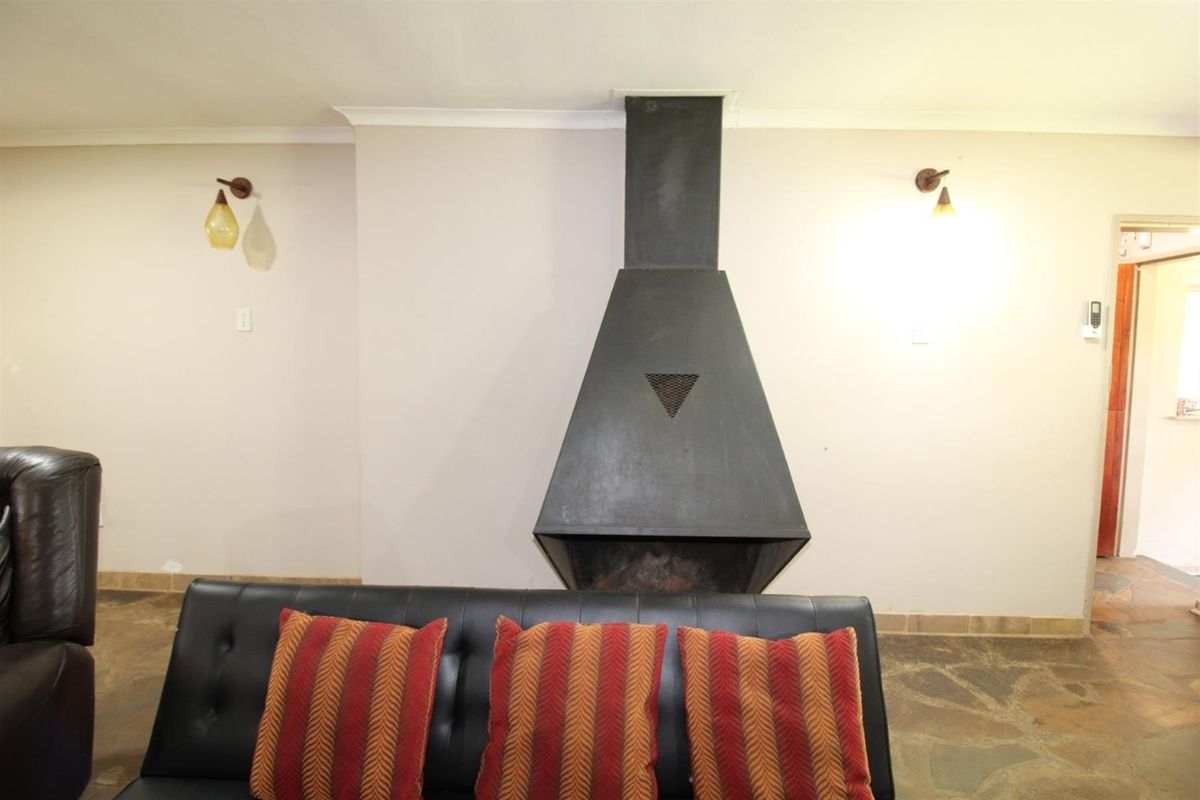 A living room featuring a prominent black metal fireplace and rustic stone flooring, creating a cozy and traditional atmosphere.