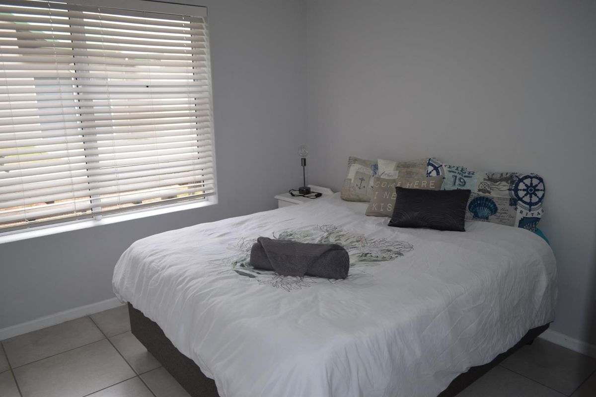 A well-maintained bedroom featuring neutral wall tones, tiled flooring, and horizontal window blinds, providing a clean and functional living space.