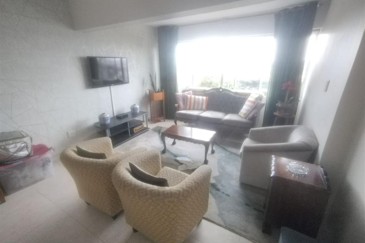 A living room featuring tiled flooring and a large window that provides natural light to the space.