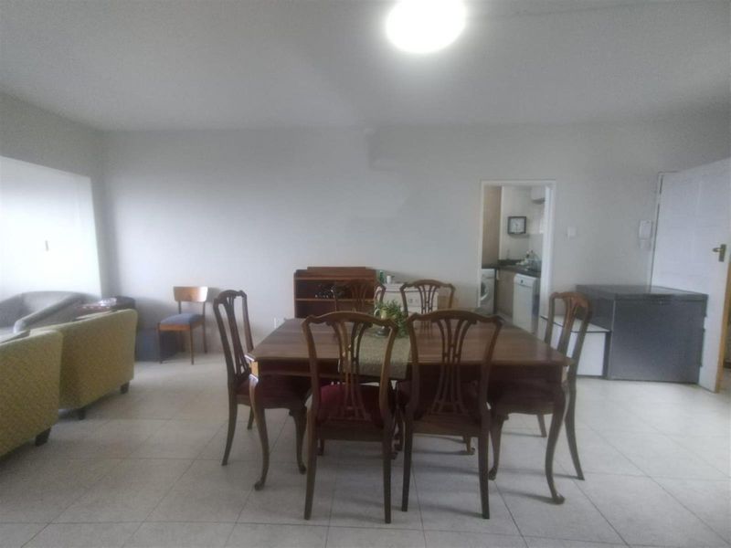 Open plan living and dining area featuring neutral tiled flooring and access to an adjacent kitchen space.