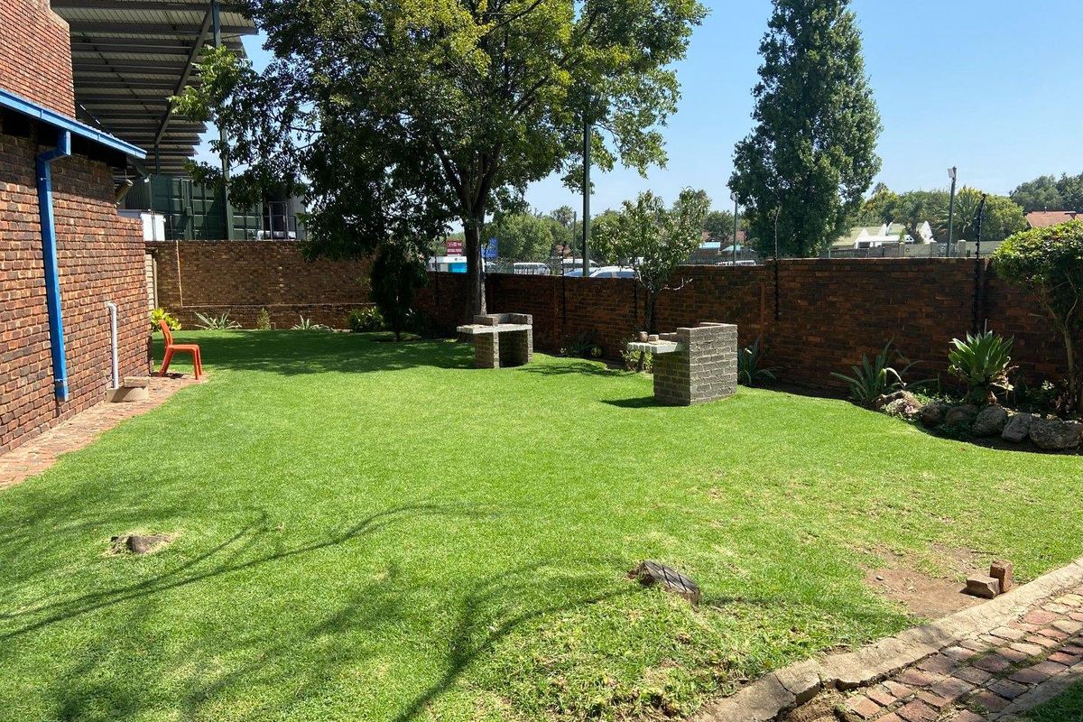 A private rear garden featuring a well-maintained lawn, perimeter brick walling, and a built-in brick braai area.