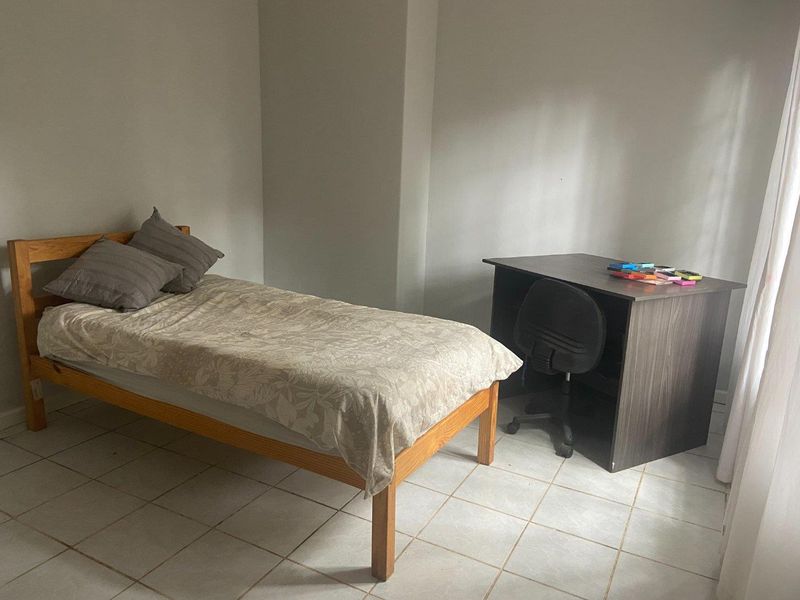 A simple bedroom featuring tiled flooring and neutral wall finishes, providing a functional and versatile living space.