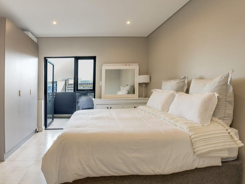 A well-maintained bedroom featuring neutral tones, built-in cupboards, tiled flooring, and direct access to a private balcony.