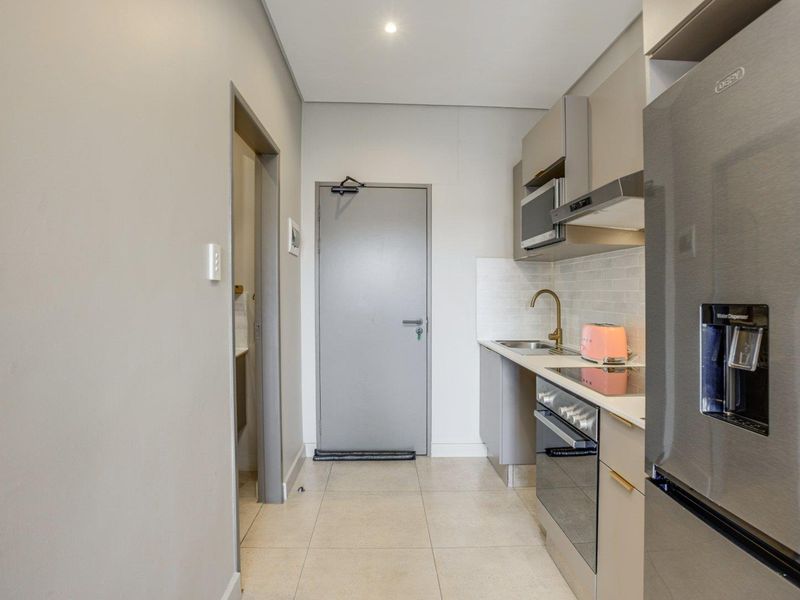 Modern galley-style kitchen featuring sleek cabinetry, integrated appliances, subway tile backsplash, and high-quality brass fixtures.