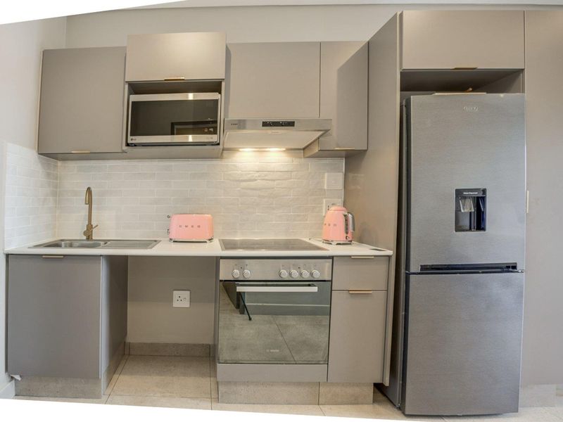 Modern kitchen featuring sleek grey cabinetry, subway tile backsplash, integrated appliances, and stone countertops in a compact, functional layout.