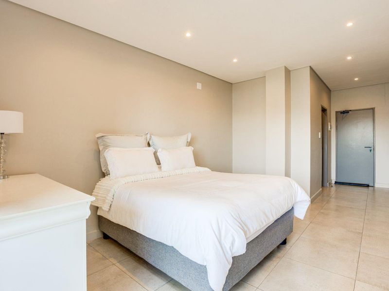 A well-maintained bedroom featuring neutral wall tones, recessed downlighting, and tiled flooring, providing a clean and modern living space.
