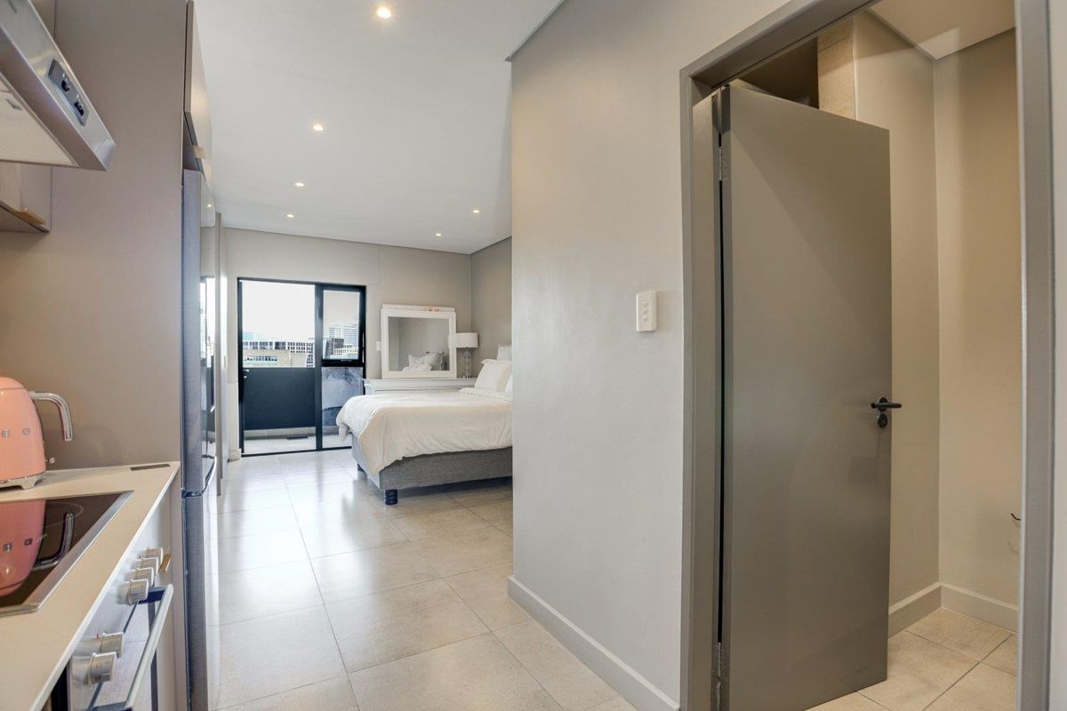 Modern open-plan apartment layout featuring a compact kitchen area flowing into a bedroom space with access to a private balcony.