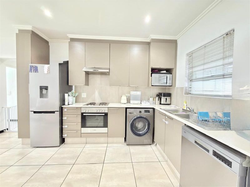 Modern kitchen featuring neutral cabinetry, integrated appliances, tiled flooring, and ample counter space with a functional layout.