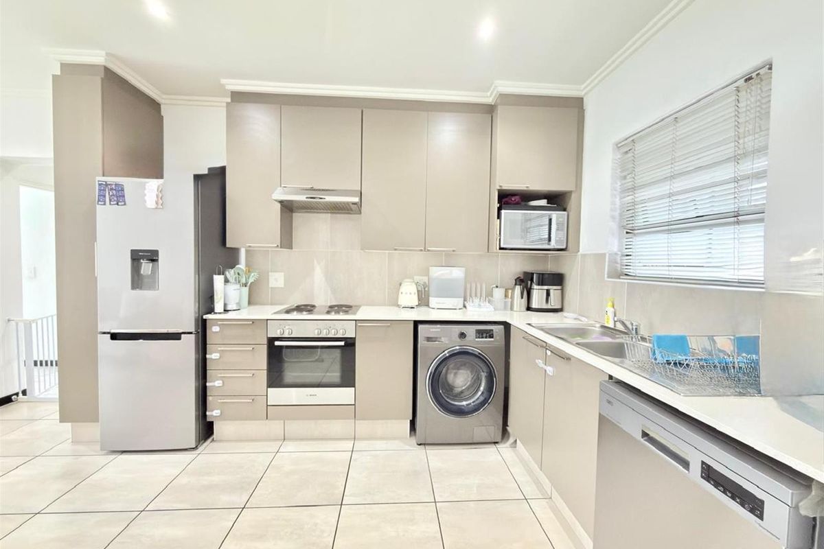 Modern kitchen featuring neutral cabinetry, integrated appliances, tiled flooring, and ample counter space with a functional layout.