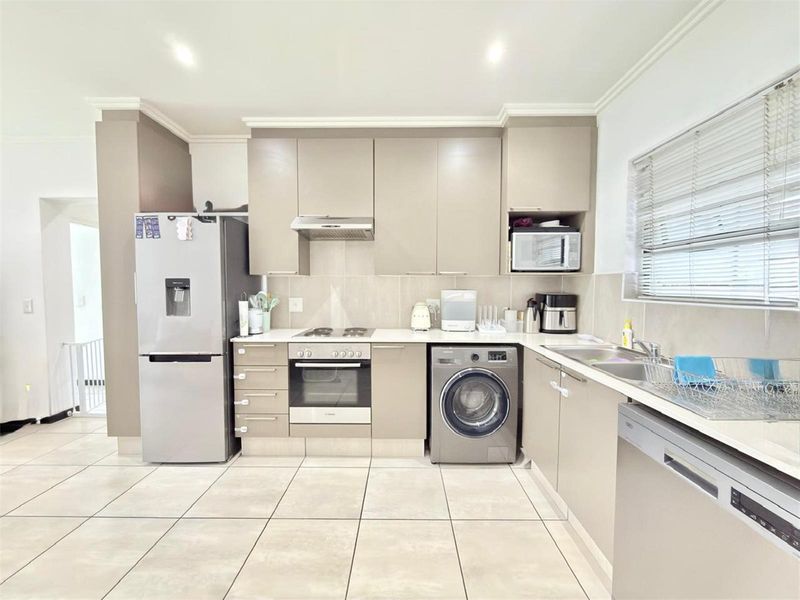 Modern kitchen featuring neutral cabinetry, integrated appliances, tiled flooring, and ample counter space, providing a functional and well-maintained culinary area.