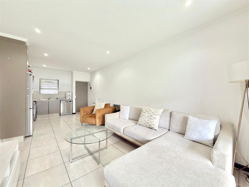 An open-plan living area featuring tiled flooring, recessed lighting, and a functional kitchen space with built-in cabinetry.