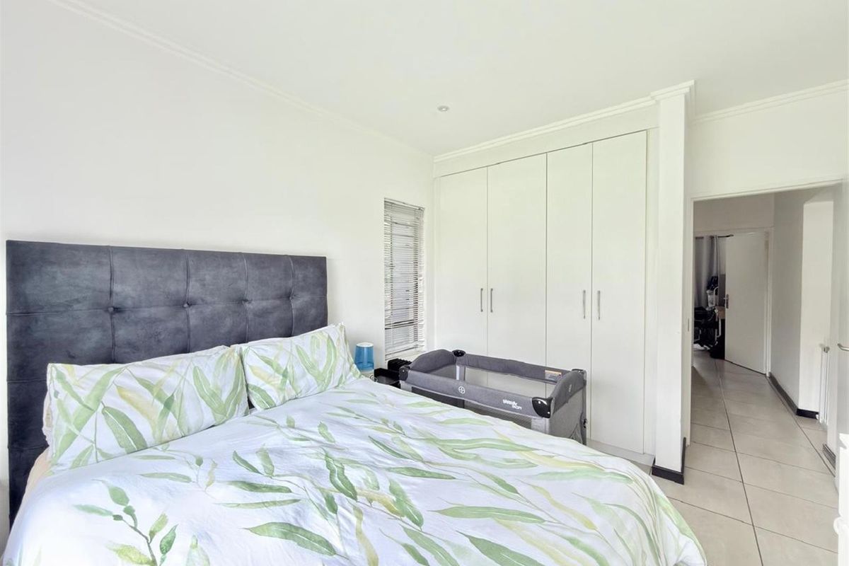 A well-maintained bedroom featuring neutral tiled flooring, built-in white cabinetry, and recessed lighting, offering a clean and functional living space.