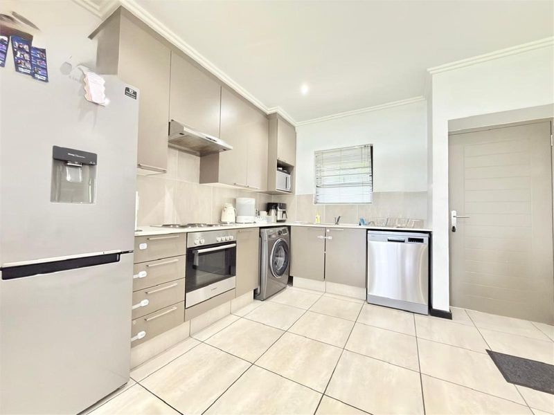 Modern kitchen featuring sleek cabinetry, stone countertops, integrated oven, hob, extractor fan, and tiled flooring with a functional layout.