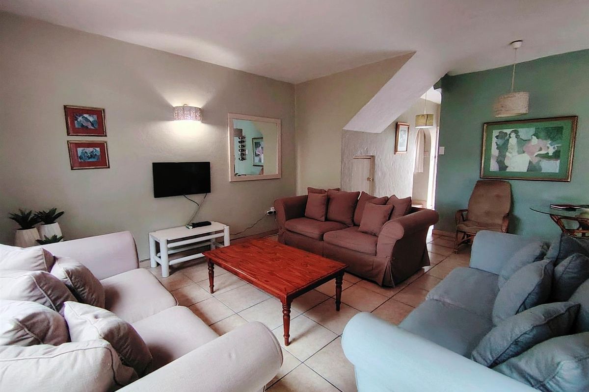 A comfortable living room featuring neutral wall tones, tiled flooring, and a unique architectural alcove, providing a cozy and functional space for relaxation.