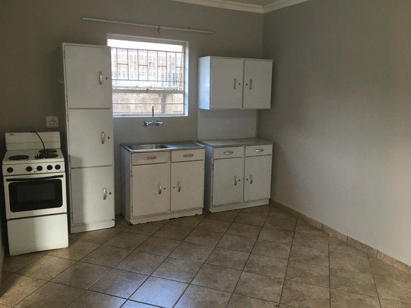 A functional kitchen featuring tiled flooring, built-in cabinetry, a stainless steel sink, and a freestanding stove, ready for modernization.