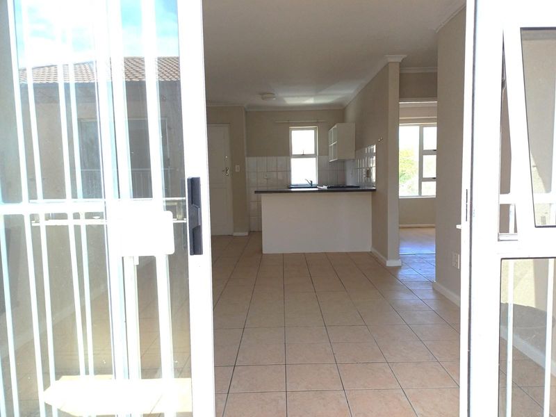 Open plan living area and kitchen featuring tiled flooring, breakfast counter, and direct access to an outdoor patio through sliding glass doors.