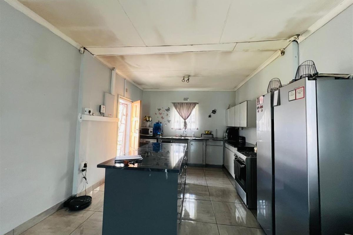 A functional kitchen featuring a central island, tiled flooring, and built-in cabinetry, requiring some ceiling maintenance to restore its appearance.