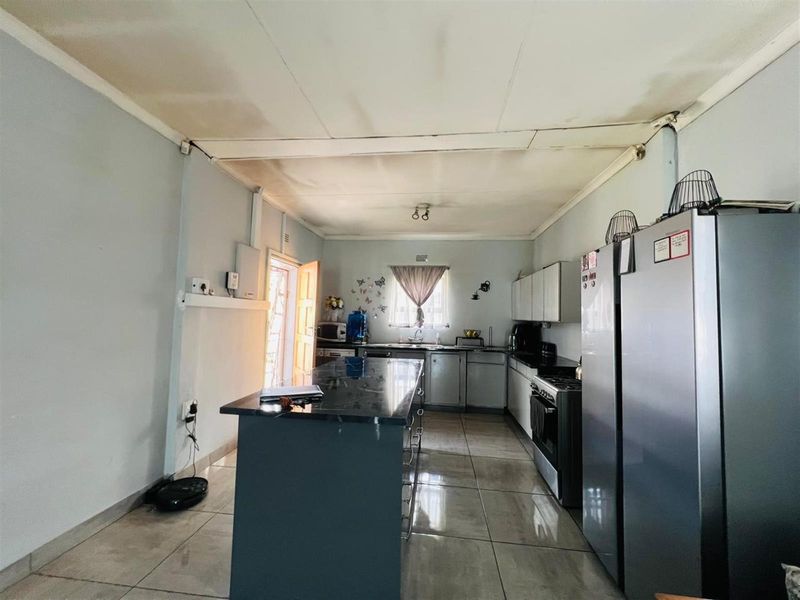 A functional kitchen featuring a central island, tiled flooring, and built-in cabinetry, requiring some ceiling maintenance to restore its appearance.