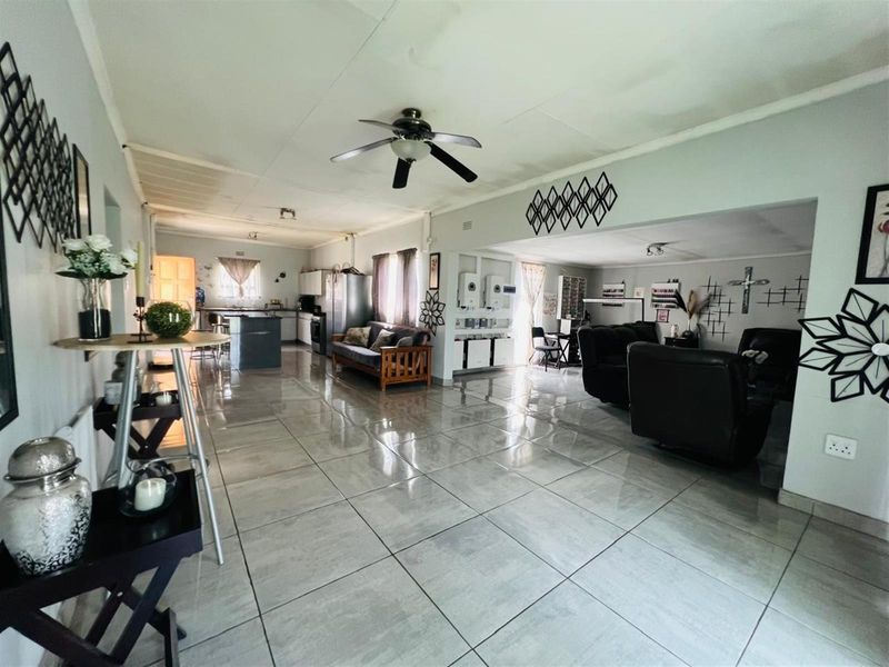 Spacious open-plan living area featuring large format floor tiles, a central kitchen island, and integrated living and dining zones with a ceiling fan.